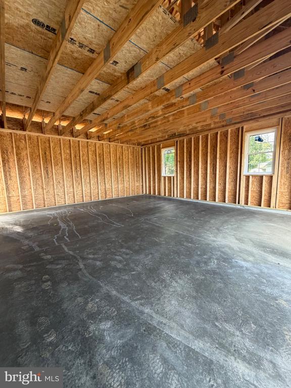 Unfinished room with a concrete floor, exposed framing, and two windows.