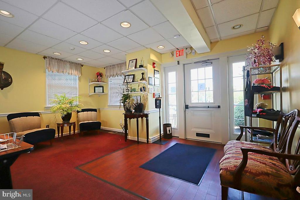 Commercial lobby with waiting chairs, plants, and glass entrance doors.