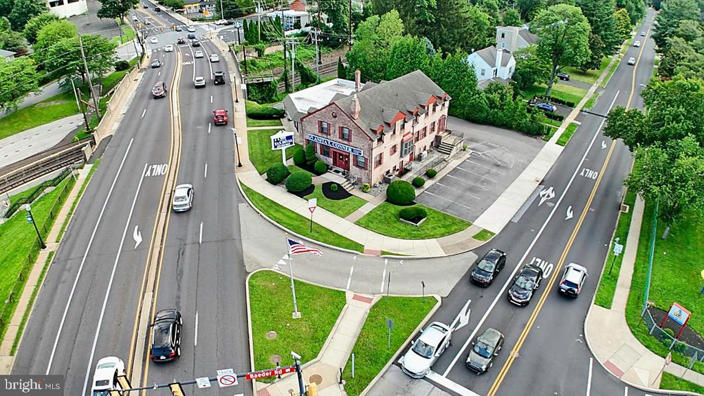 Aerial view of a brick commercial building beside a busy intersection and parking lot.