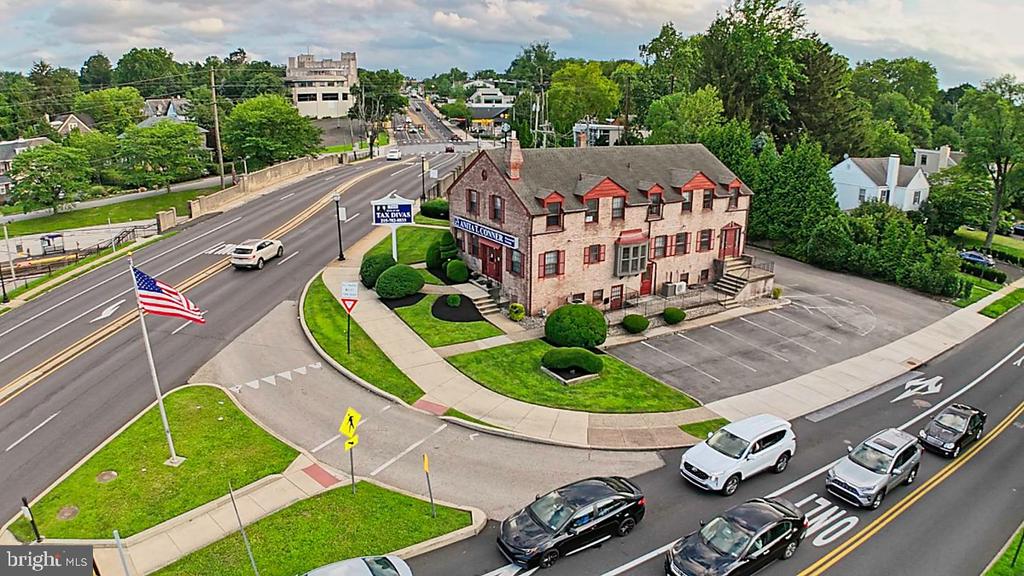 Aerial view of a stone commercial building with red shutters, landscaped grounds, and a surrounding parking lot.