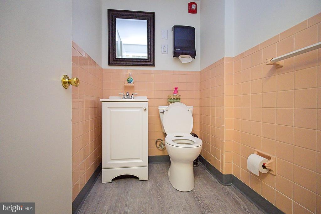 Bathroom with peach-pink tile, white vanity and toilet, and a dark-framed mirror.