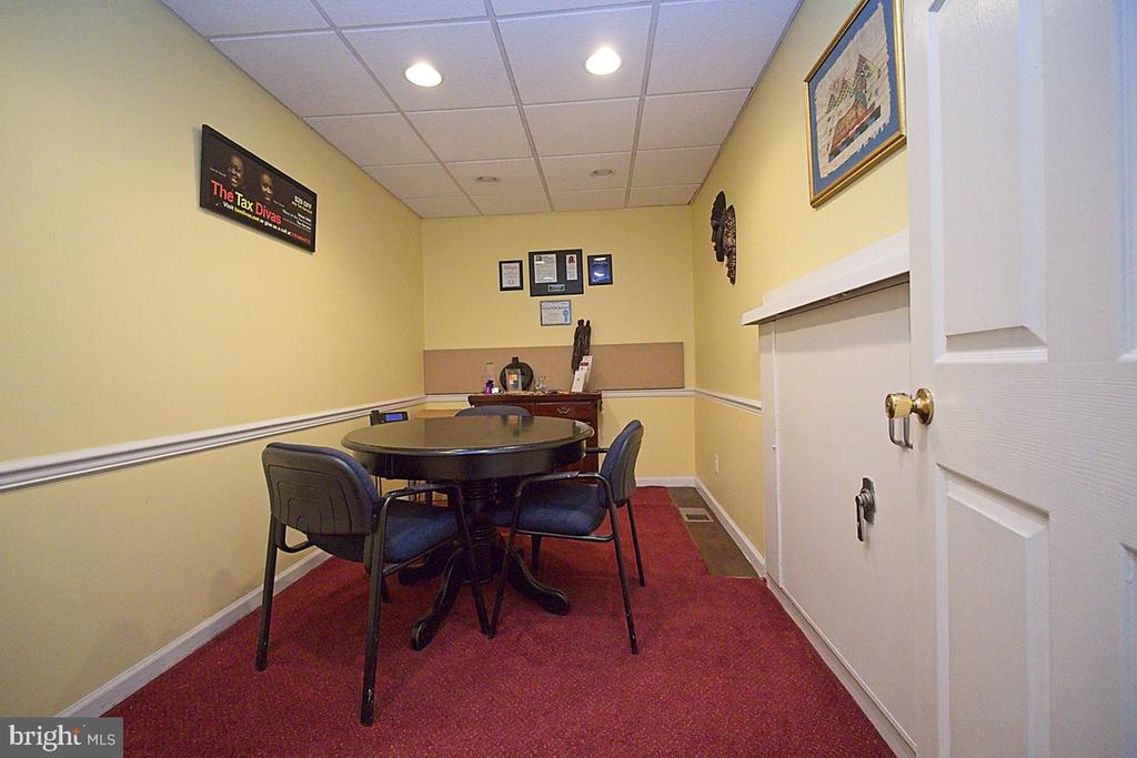 Office meeting room with a round table, chairs, yellow walls, and red carpet.