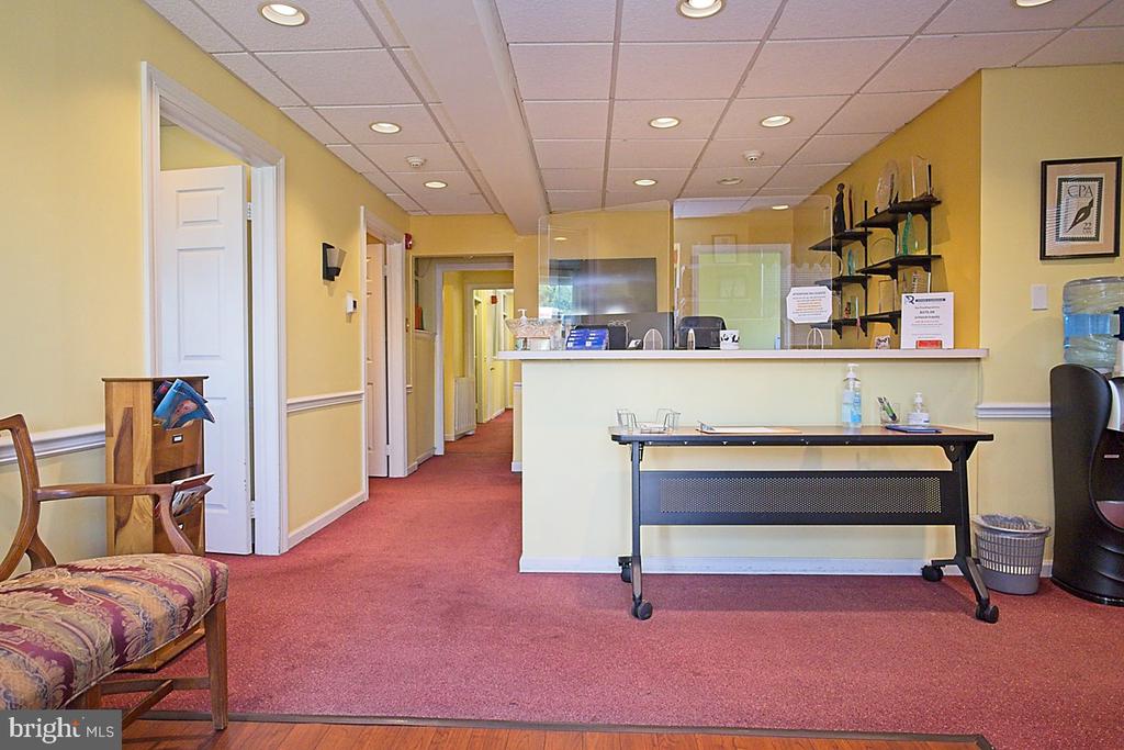 Office reception area with a cream counter, red carpeting, and a hallway behind the desk.