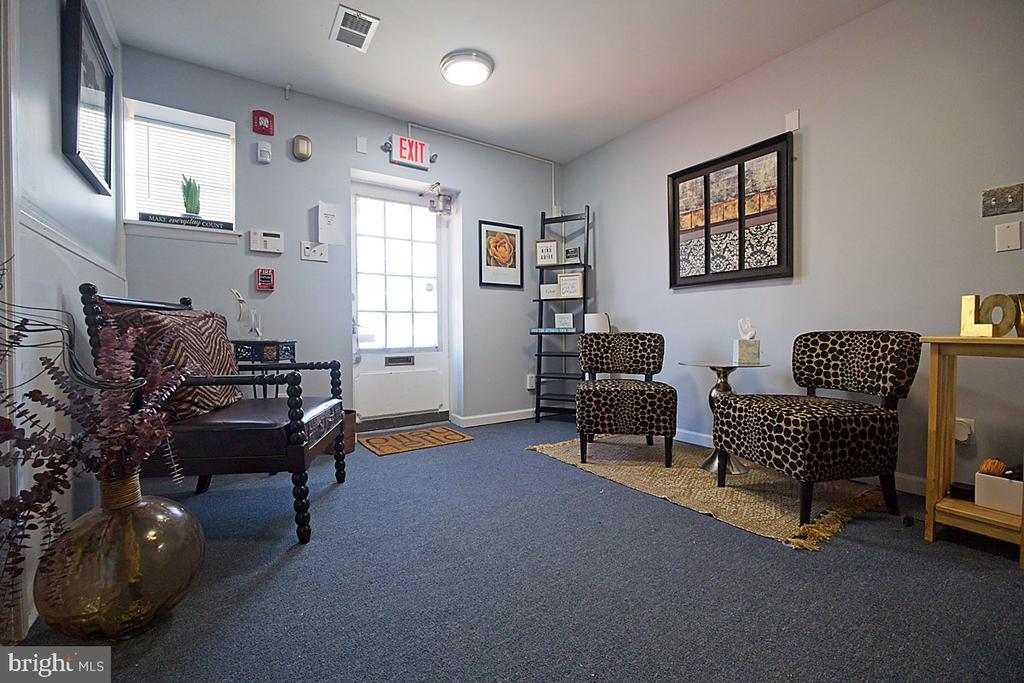 Furnished waiting area with patterned chairs, a leather bench, and a glass-paneled exit door.