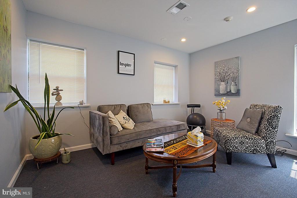 Furnished sitting room with a gray sofa, patterned armchair, and round wooden coffee table.