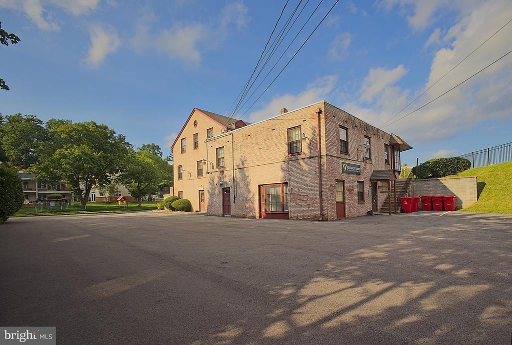 Two-story brick commercial building beside a broad paved parking area and exterior stairs.