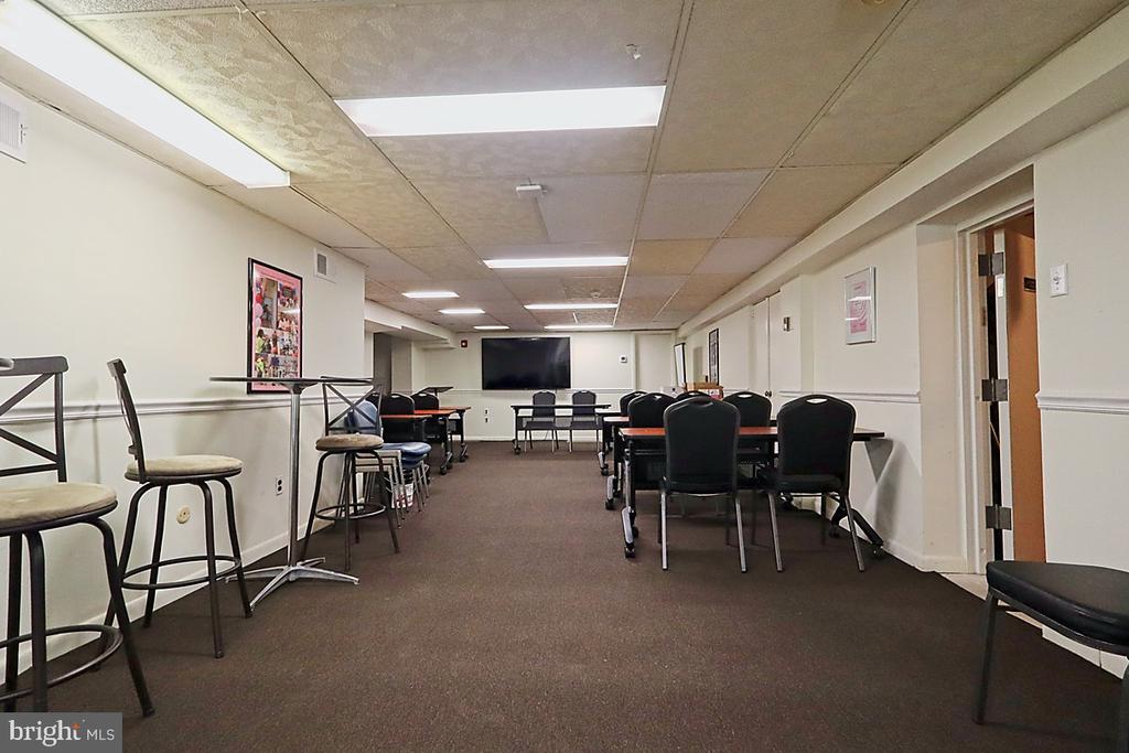 Meeting room with rows of tables and chairs and a television at the far end.
