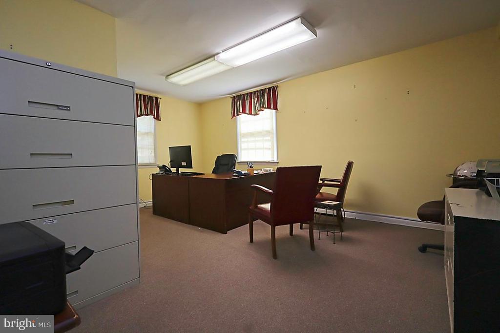 Office with a large wooden desk, chairs, filing cabinets, and two windows.