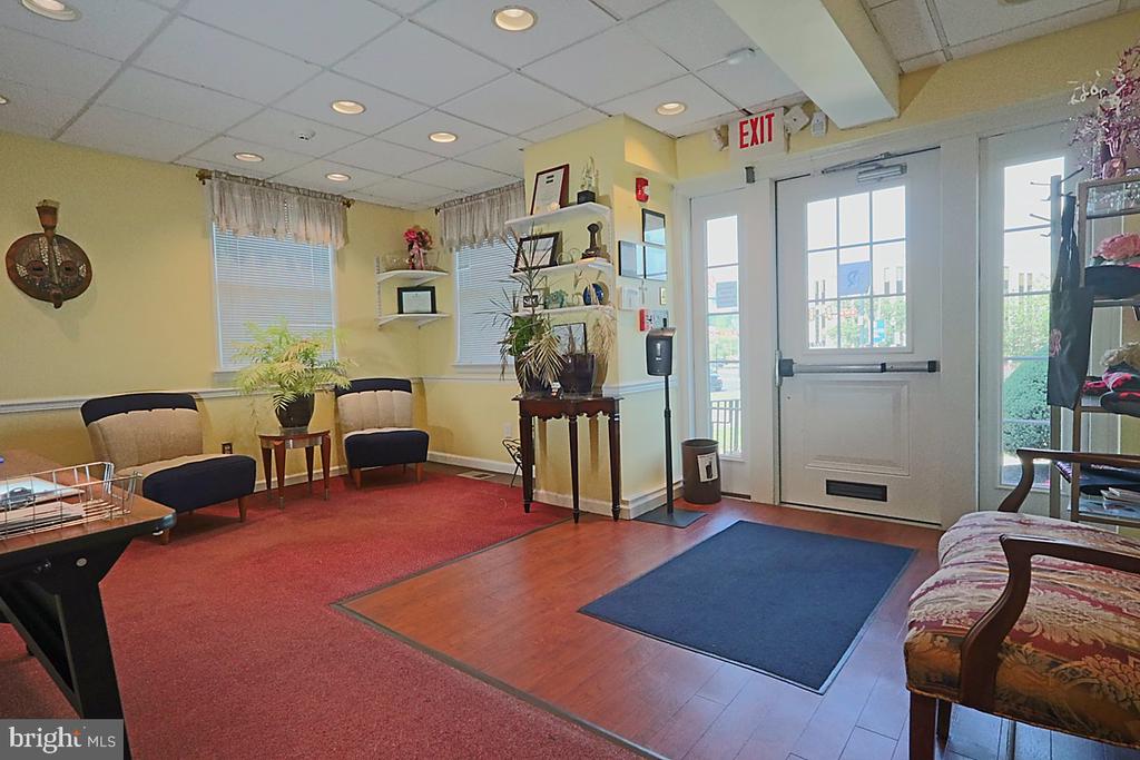 Furnished reception area with waiting chairs, potted plants, and a glass entrance door.