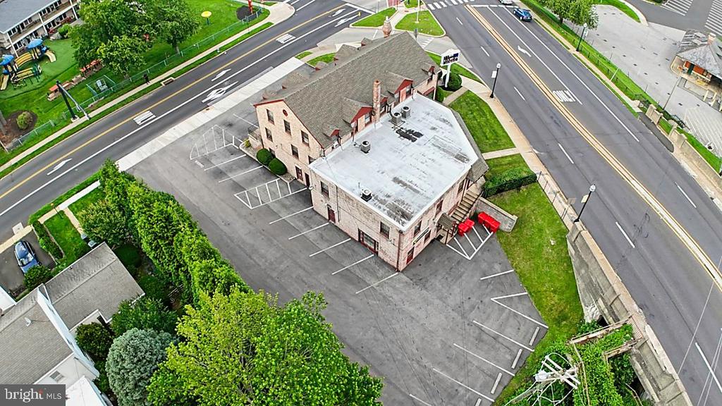 Commercial building with a flat-roofed addition and parking lot at a road intersection.