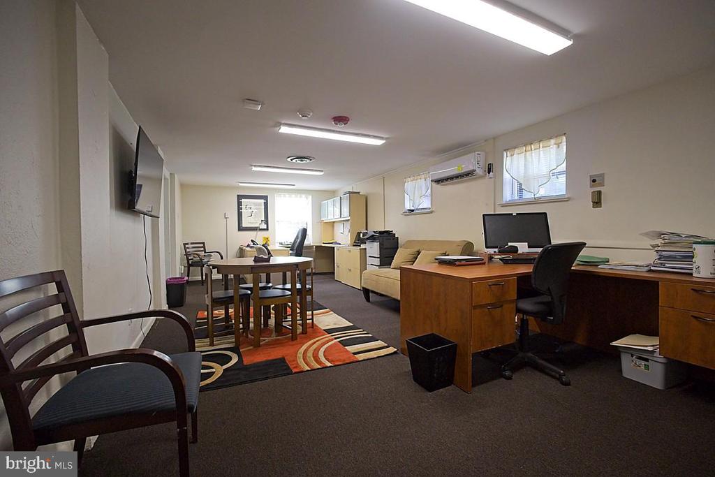 Furnished office with wooden desks, a conference table, and a sofa.