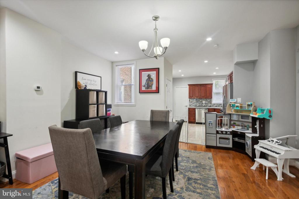 Dining room with a dark table and gray chairs opening into a wood-cabinet kitchen.