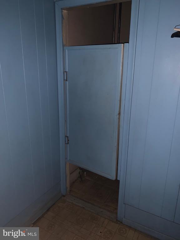 Blue paneled interior doorway with a short swinging door and patterned flooring.