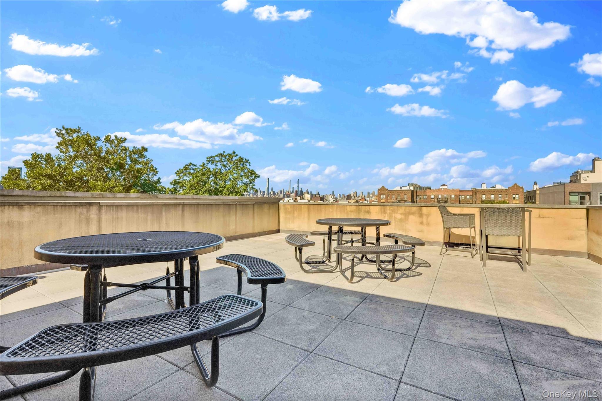 Rooftop terrace with picnic tables and chairs overlooking a distant city skyline.