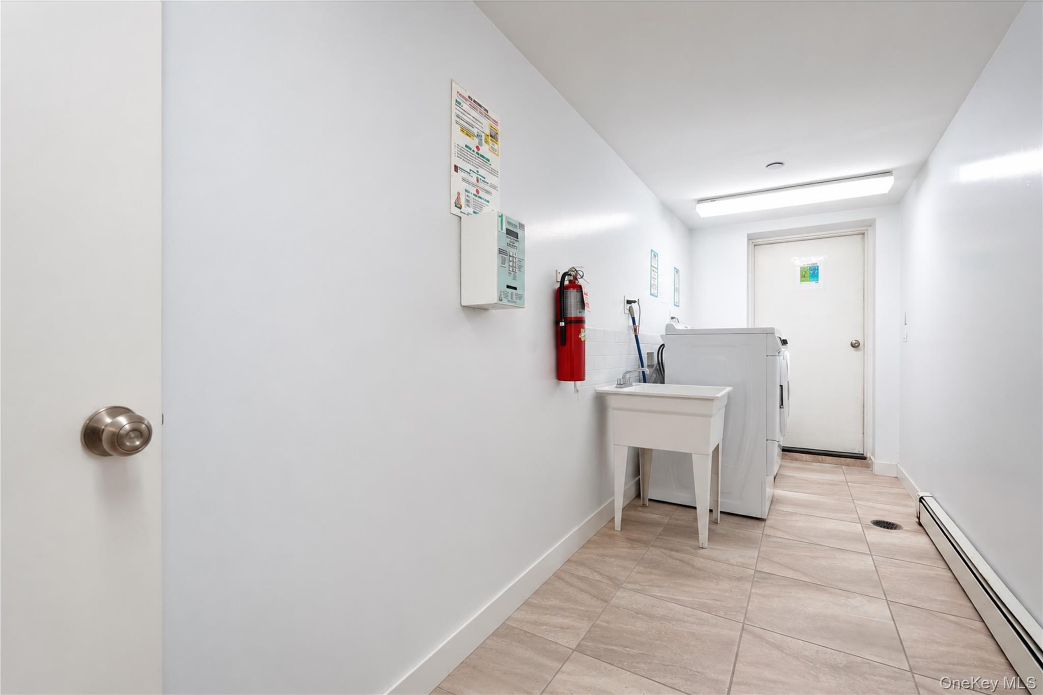 Laundry room with a washing machine, utility sink, and tiled floor.