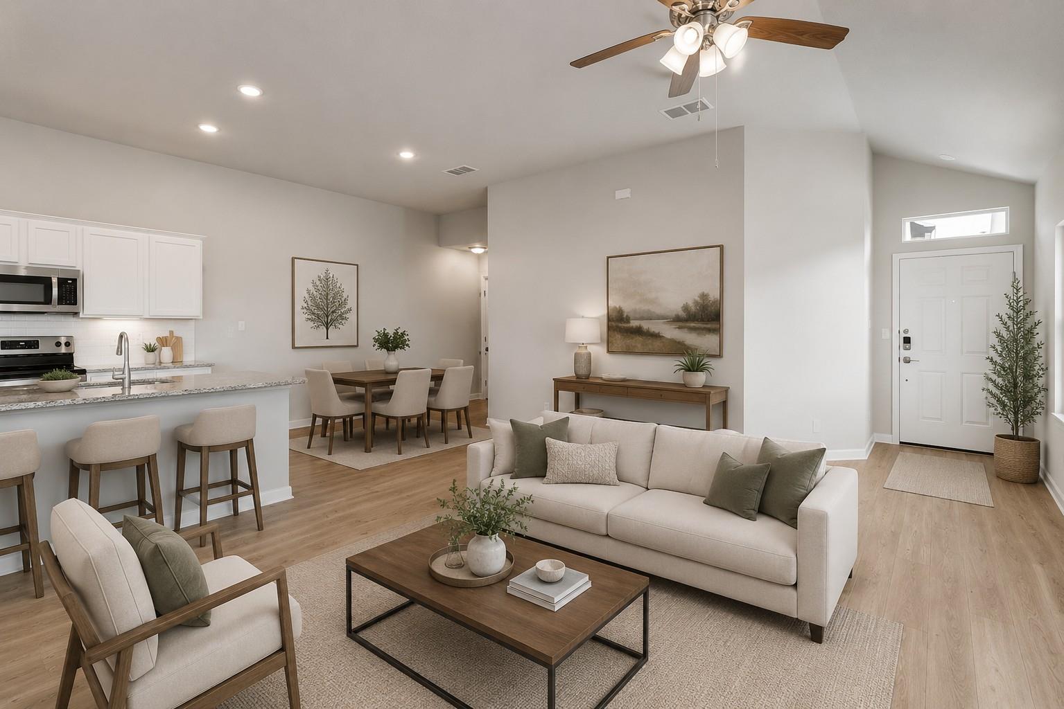 Open-plan living room with a neutral sofa, dining table, kitchen island, and wood flooring.