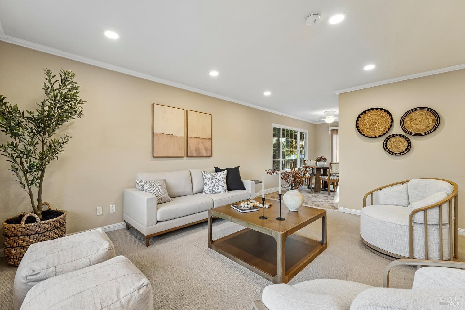 Staged living room with a white sofa, wooden coffee table, and dining area beyond.