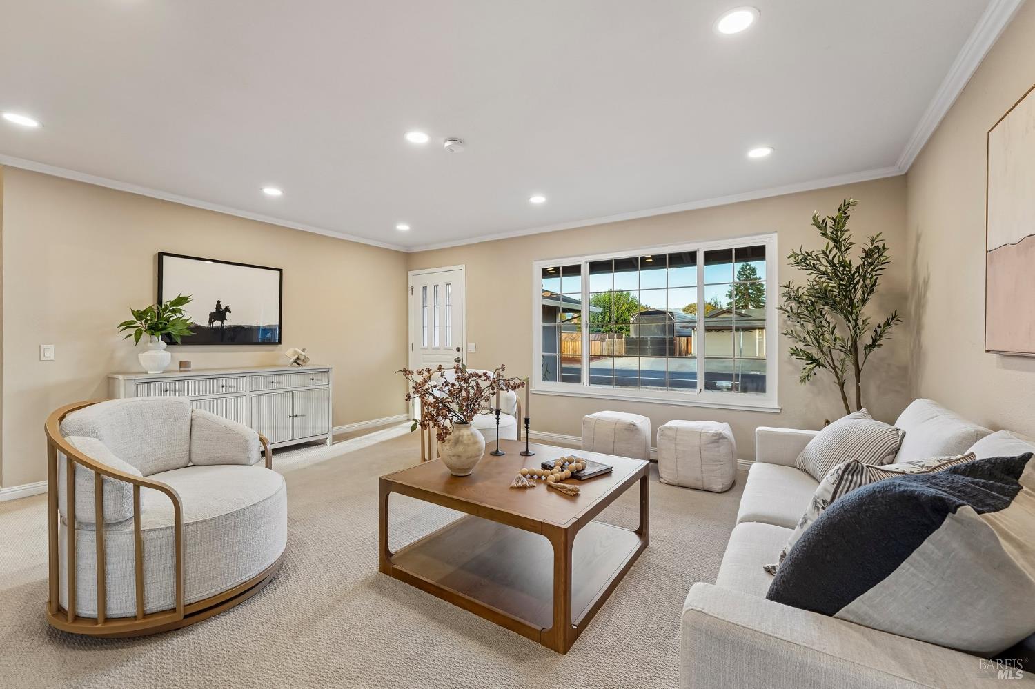 Staged living room with cream seating, a wooden coffee table, and a large backyard-facing window.