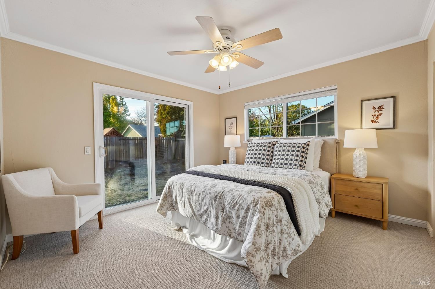 Staged bedroom with a large bed, ceiling fan, and sliding glass door to the yard.
