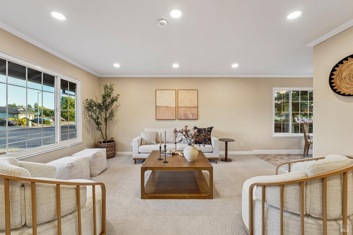 Staged living room with cream seating, a wooden coffee table, and large gridded windows.