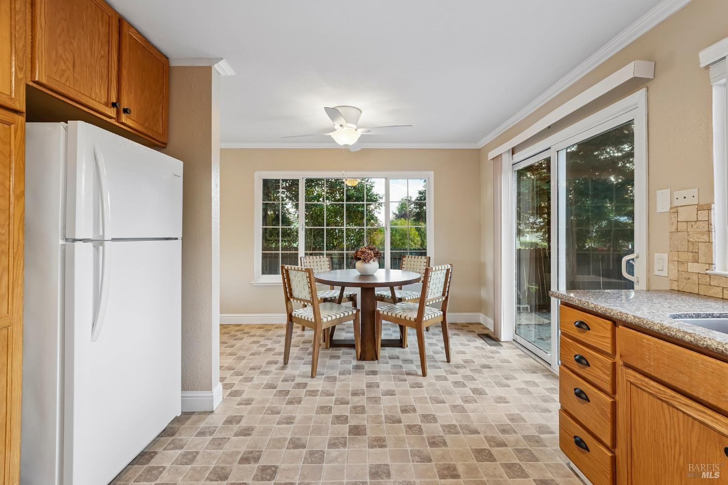 Kitchen dining area with wood cabinets, a round table, and a sliding glass door.