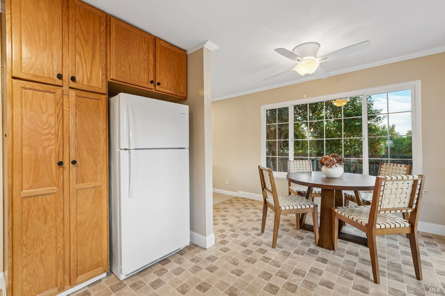 Kitchen and dining area with wood cabinets, tiled floors, and a round table by a large glass door.