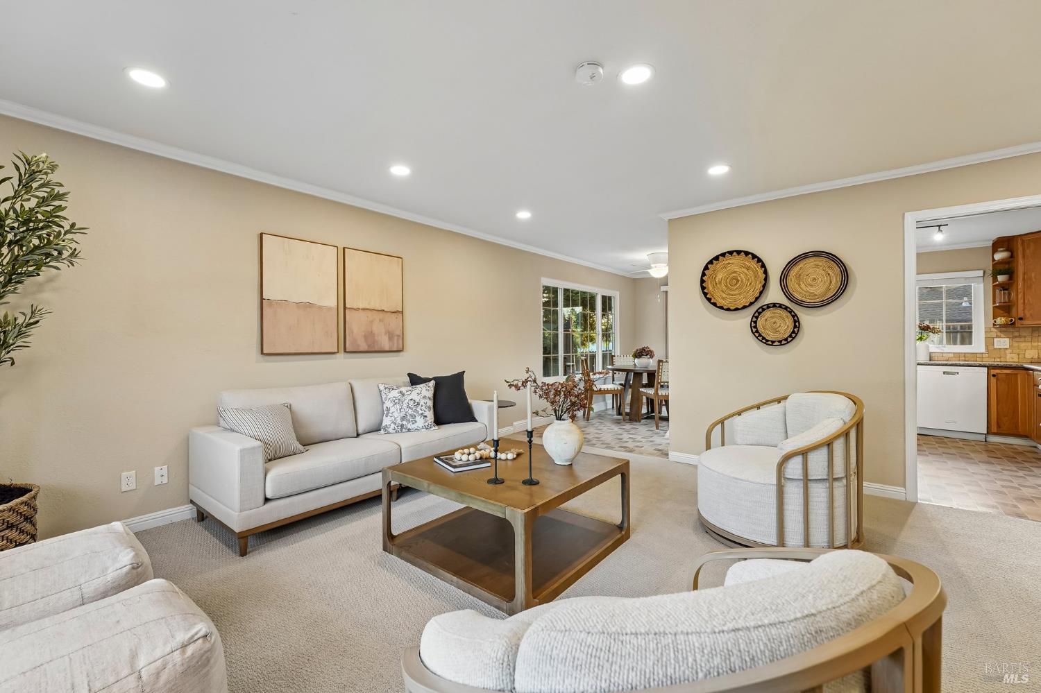 Staged living room with light seating, a wooden coffee table, and woven wall baskets.