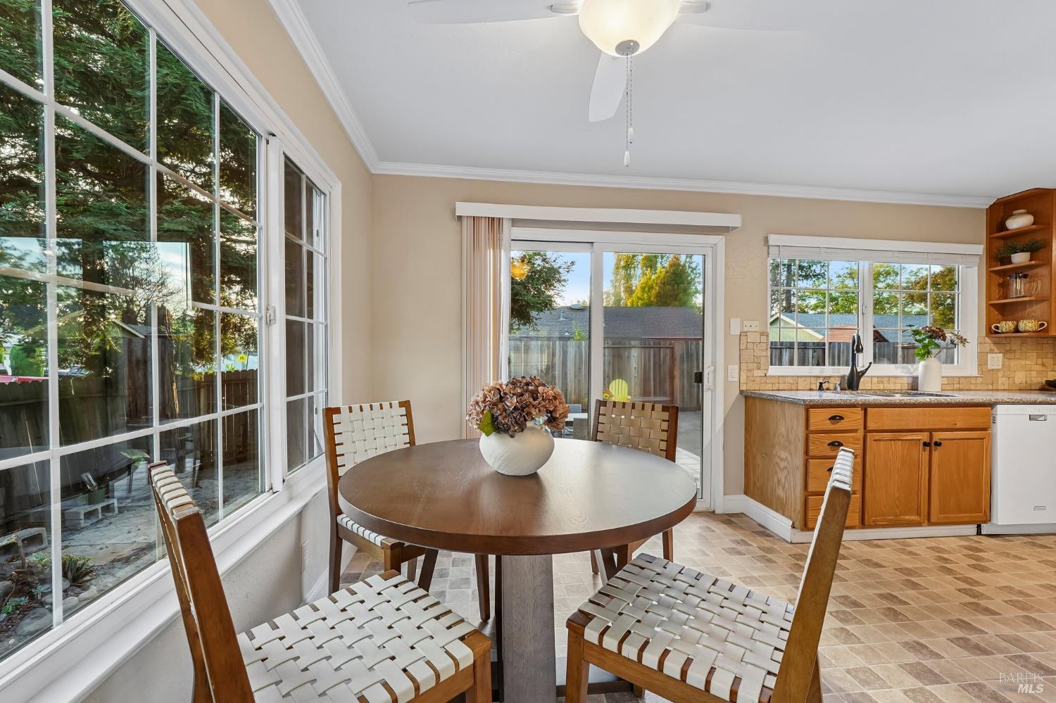 Dining area with a round wooden table beside large windows and a sliding glass door.
