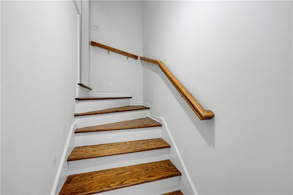 Staircase with wood treads and a matching handrail against white walls.
