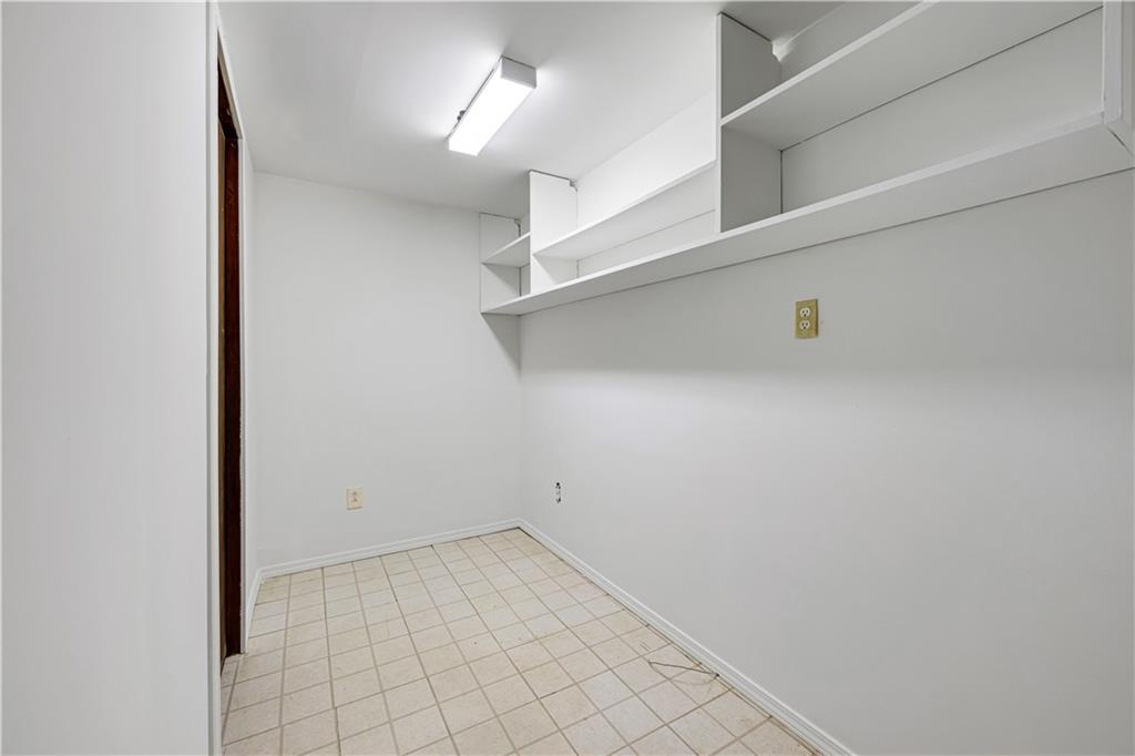 Vacant room with built-in white shelving and a tiled floor.