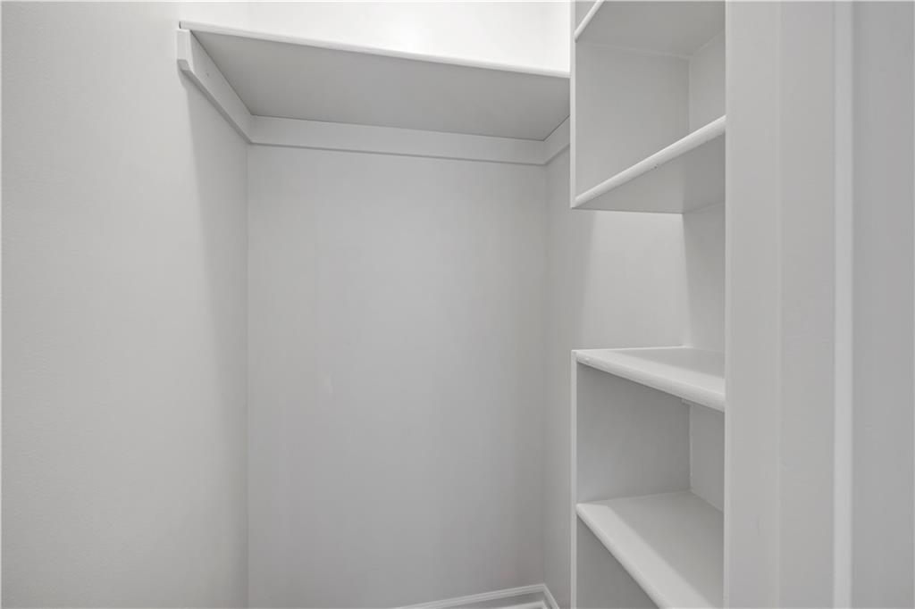 Walk-in closet with a high shelf and built-in shelving.