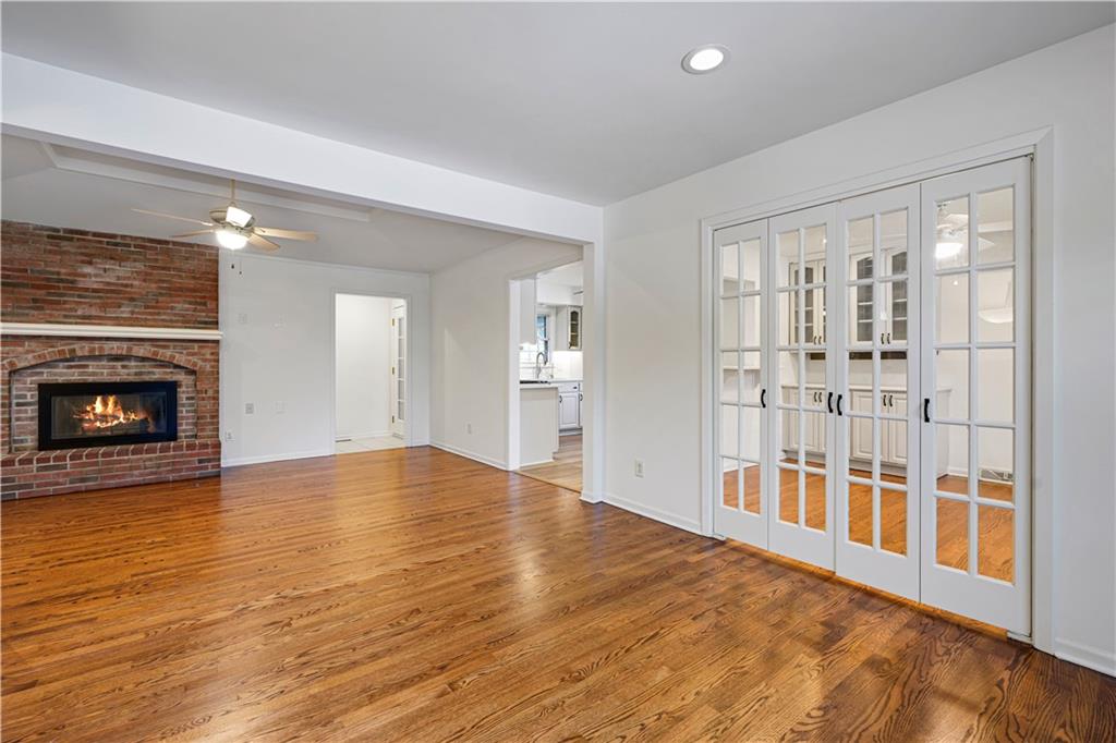 Living room with hardwood floors, a brick fireplace, and white French doors.