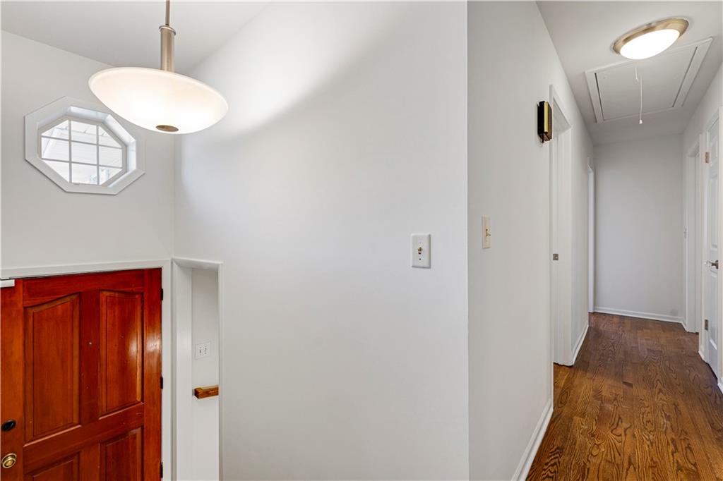 Entryway with a red wooden door, octagonal window, and hardwood hallway.