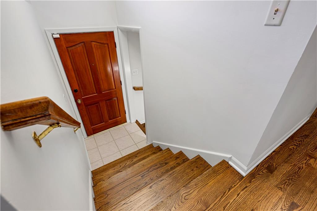 Wooden staircase descending to a tiled entry with a paneled front door.
