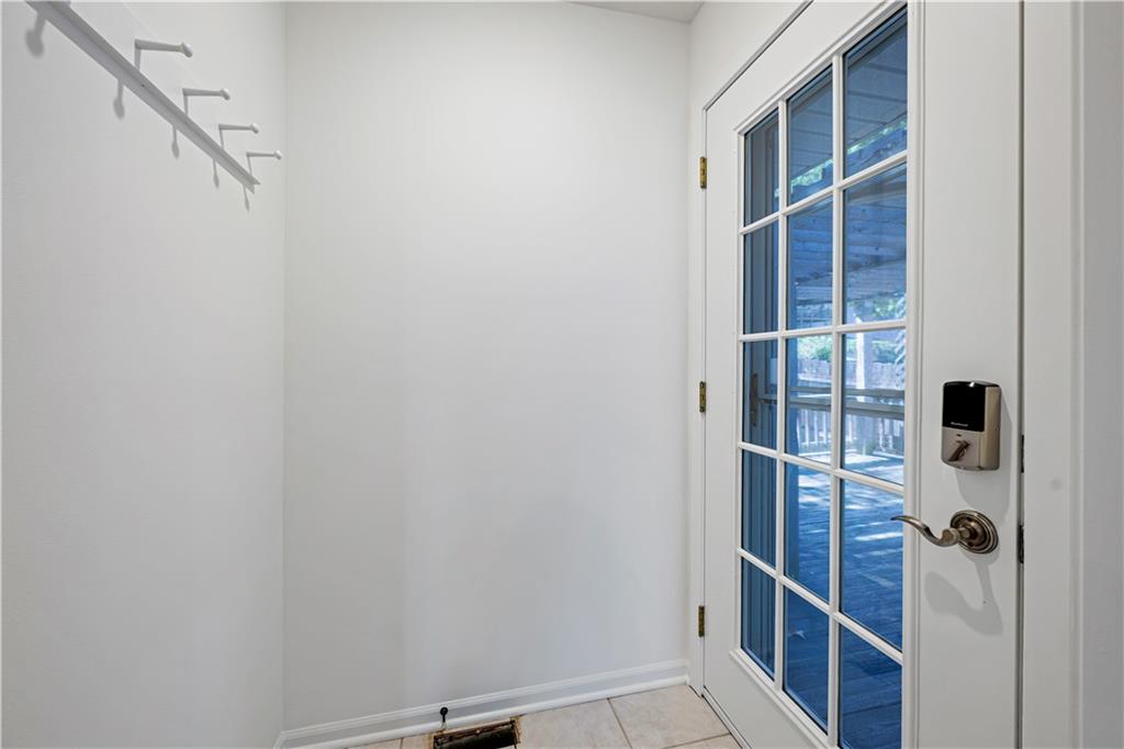 Empty entryway with wall hooks and a glass-paneled door to the deck.
