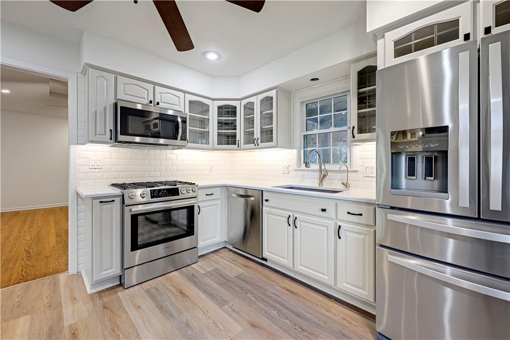 Kitchen with white cabinets, stainless steel appliances, and a sink beneath a window.