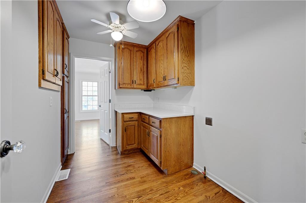 Kitchen with oak cabinets, white countertops, and hardwood flooring.