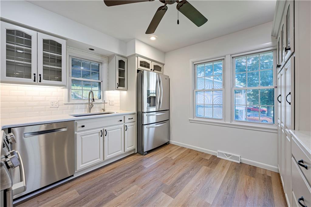 Kitchen with white cabinets, stainless steel appliances, and large windows overlooking the yard.