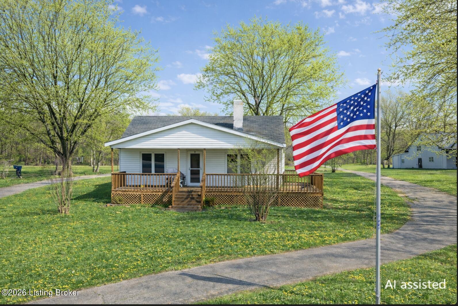 White single-story house with a covered wooden porch and a large American flag in the foreground.