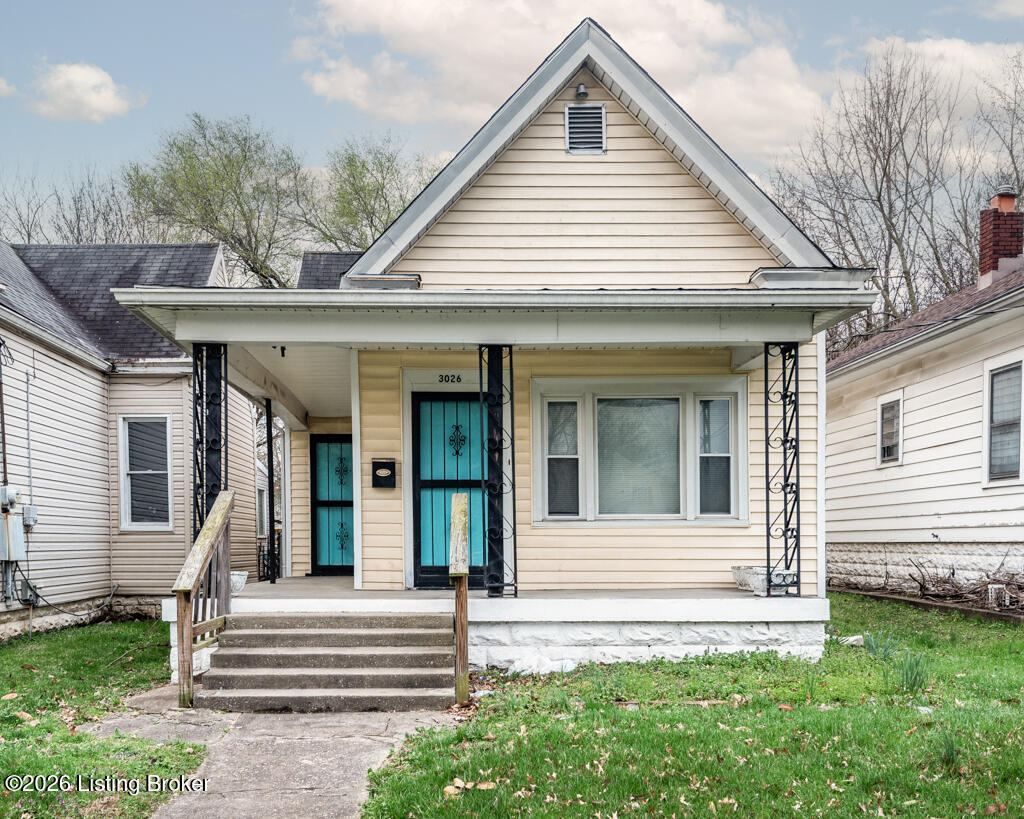 Cream-sided house with a covered porch, concrete steps, and bright turquoise doors.