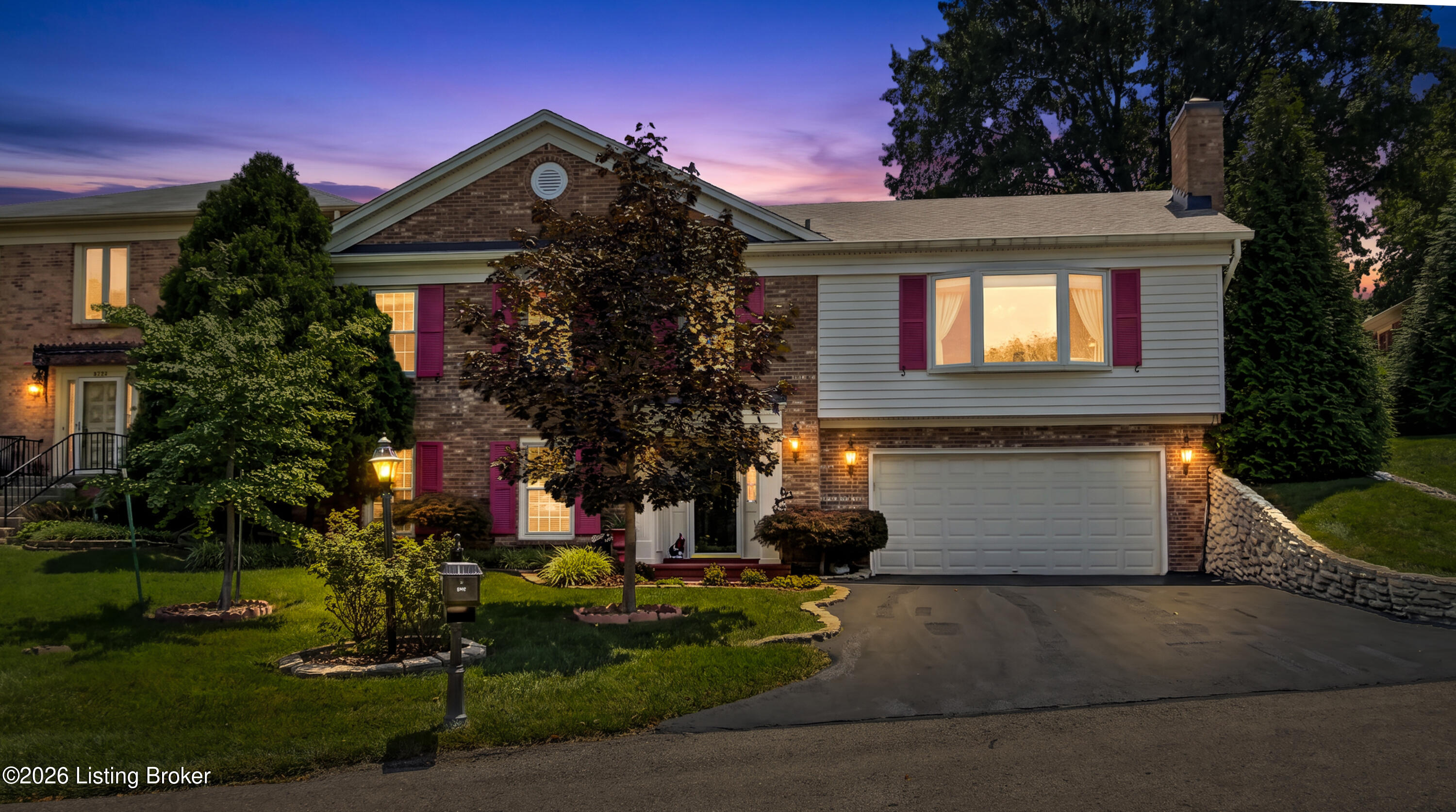 Two-story brick and siding home with magenta shutters and attached garage at dusk.