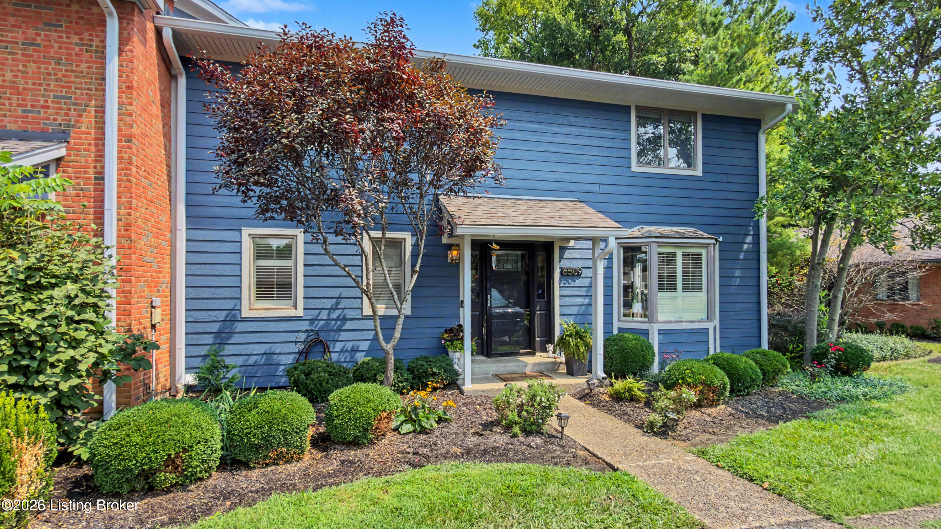 Blue-sided home with white trim, a covered entry, and landscaped front garden.