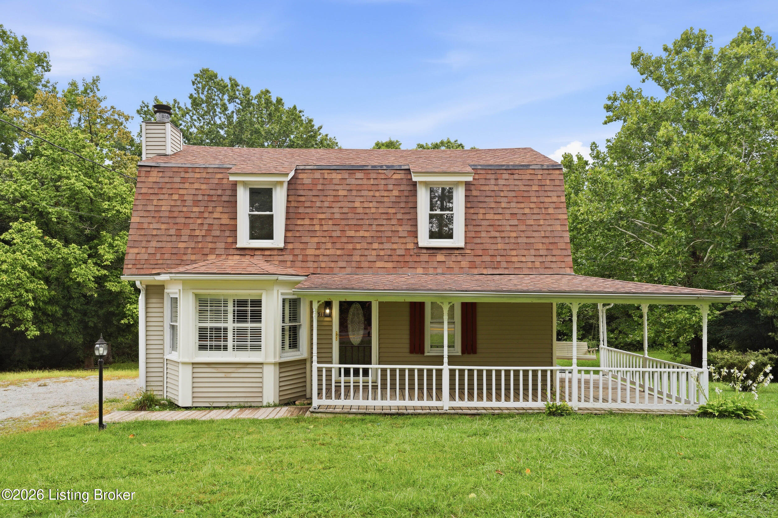 Two-story house with a shingle roof, bay window, and long covered front porch.