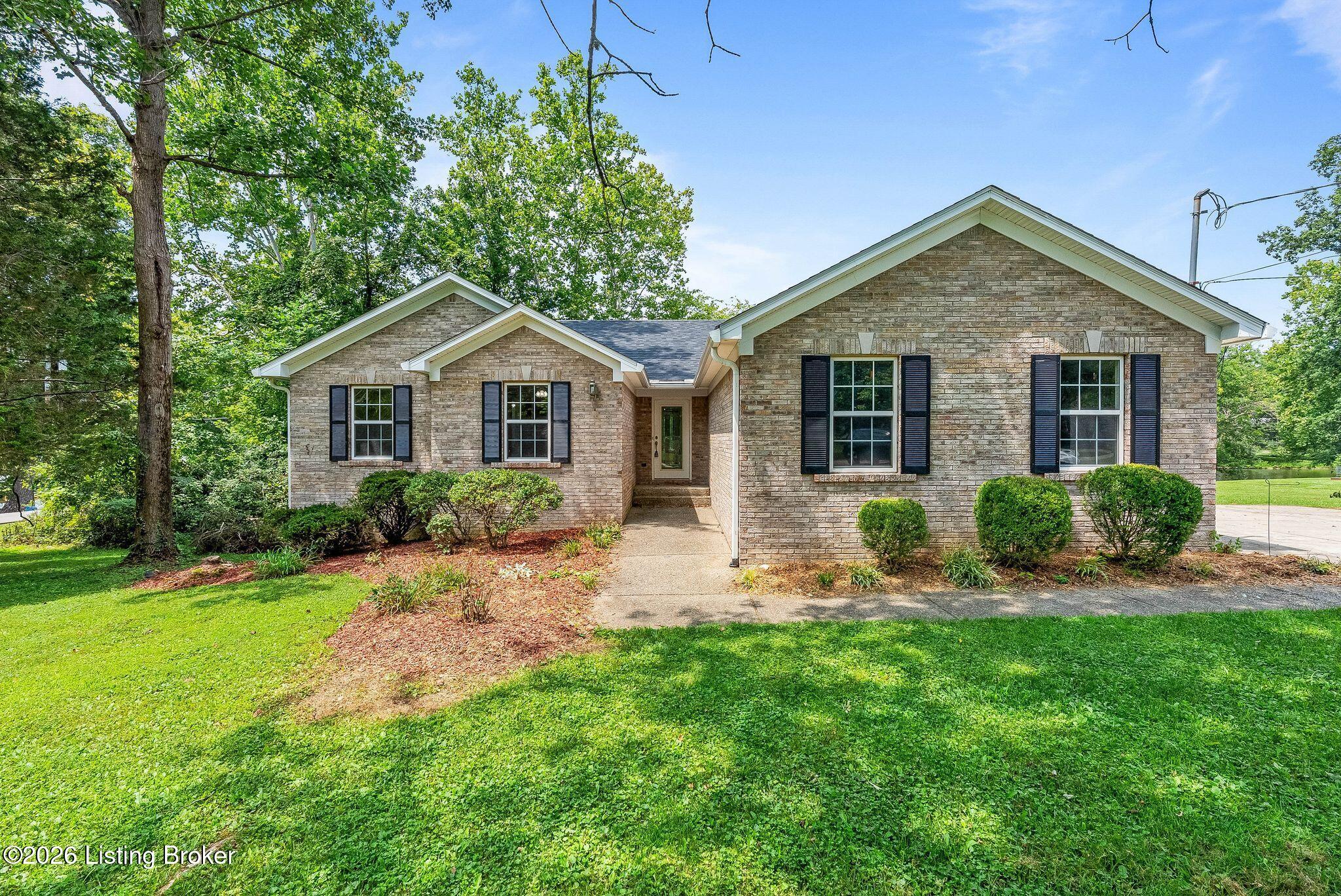 Single-story brick house with dark shutters, a recessed entry, and a green lawn.