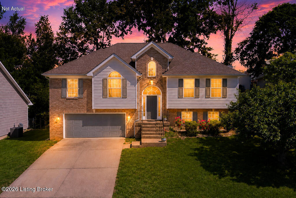 Two-story brick and siding house with illuminated windows and a double garage at dusk.