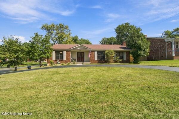 Single-story brick home with a covered entry, broad lawn, and mature trees.