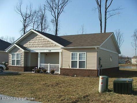 Single-story beige house with a covered front porch, gabled roof, and brick foundation.