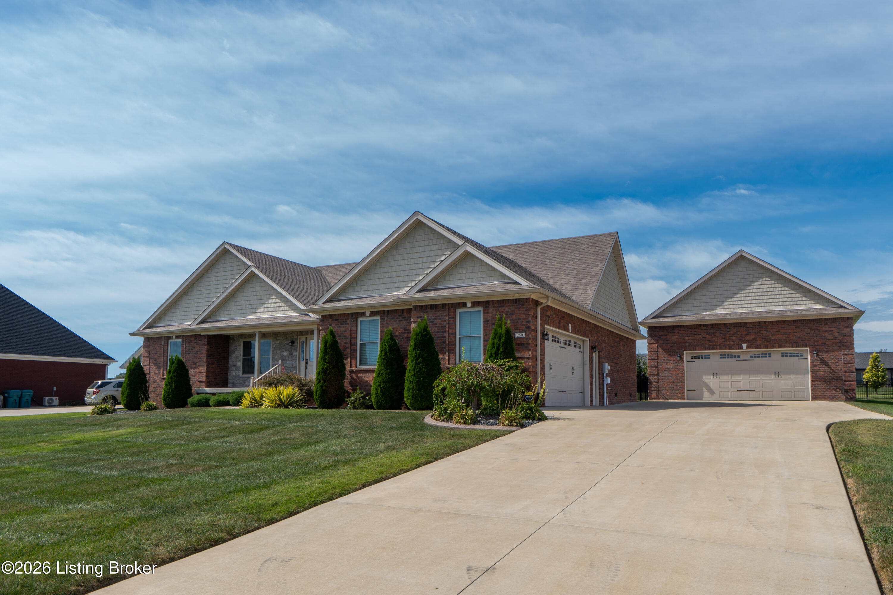 Red-brick house with multiple gables, landscaped lawn, and a broad driveway to a detached garage.