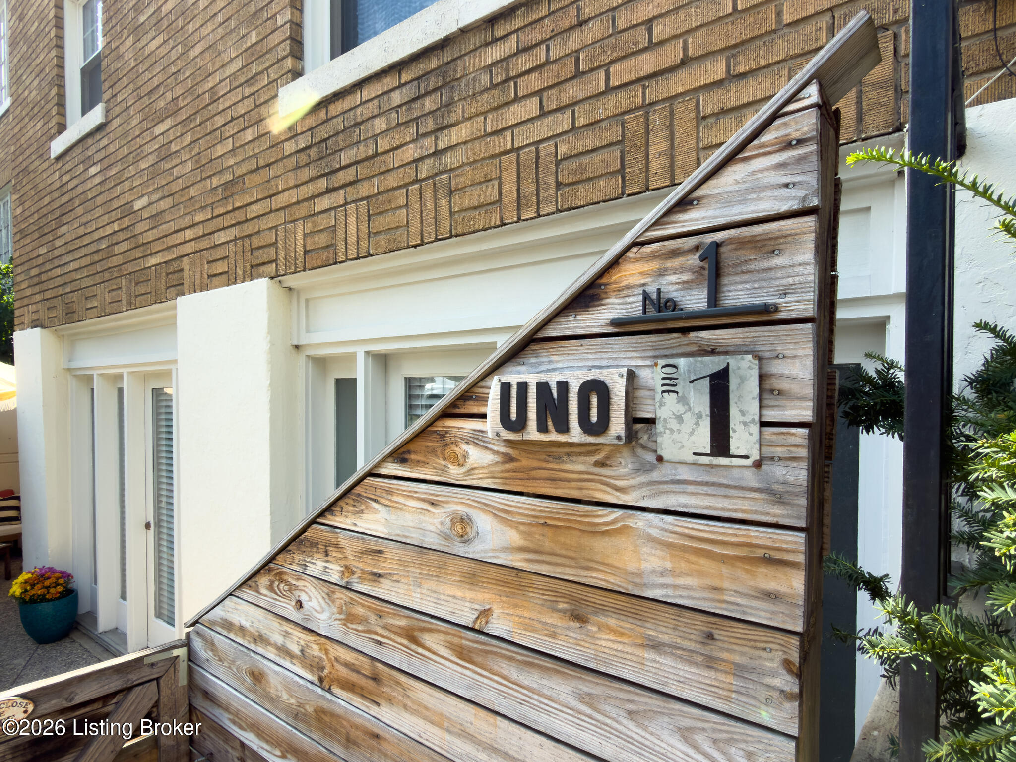 Wooden UNO No. 1 entrance sign beside a brick building.