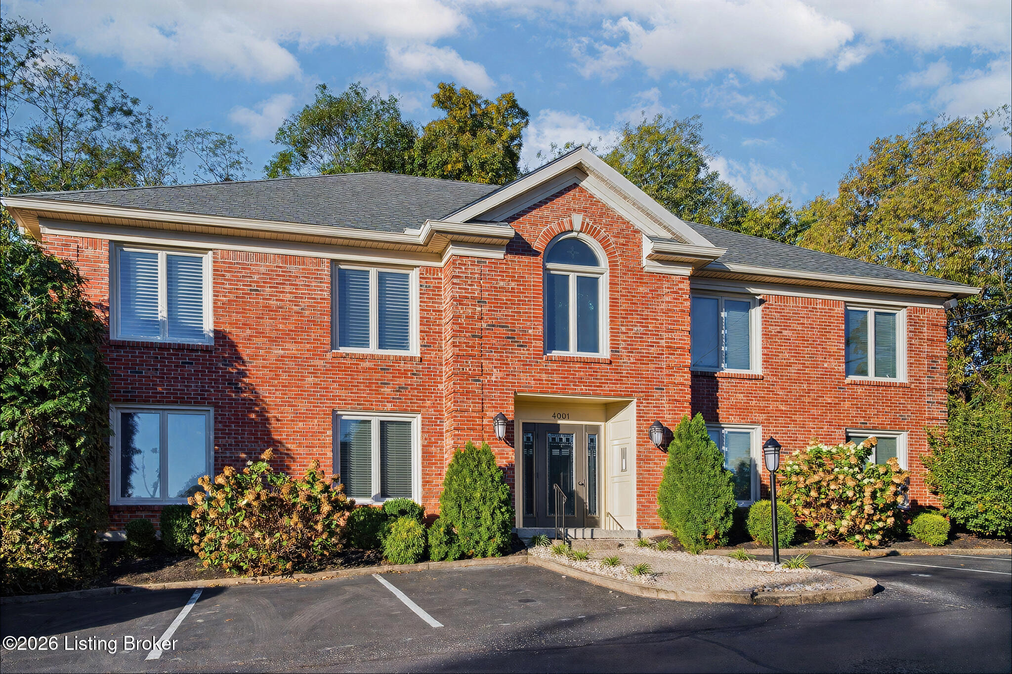 Two-story red brick building with an arched upper window and landscaped entrance.